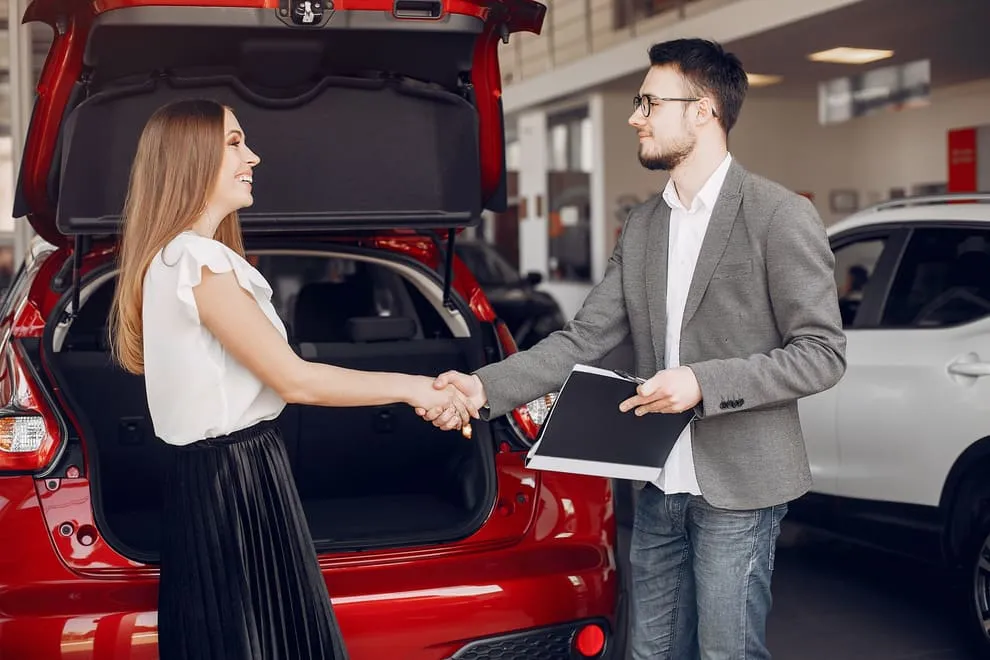 Car buyer shaking hands with a salesman at a dealership