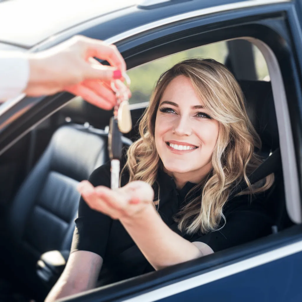 Smiling woman in the driver's seat taking the car keys