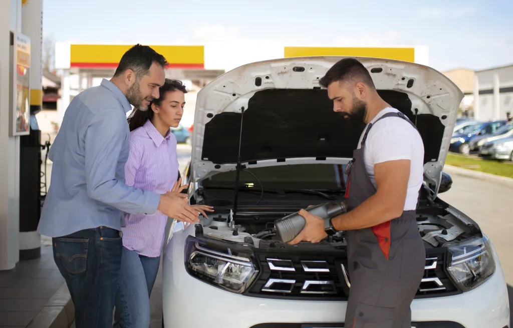Mechanic showing a couple the engine of a car at a service station