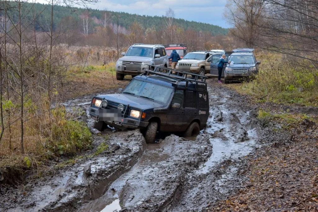 Land Rover Discovery in deep ruts on a muddy track, with other 4WDs waiting behind it